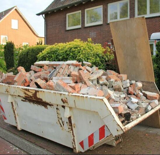bricks overflowing out of a 15 yard container beside a home